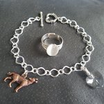 Close up detail of wolf charm and crystal heart on silver plated chain bracelet with toggle clasp